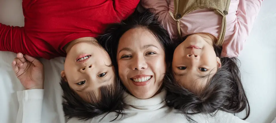 a happy smiling mother with her son and daughter looking up at the camera